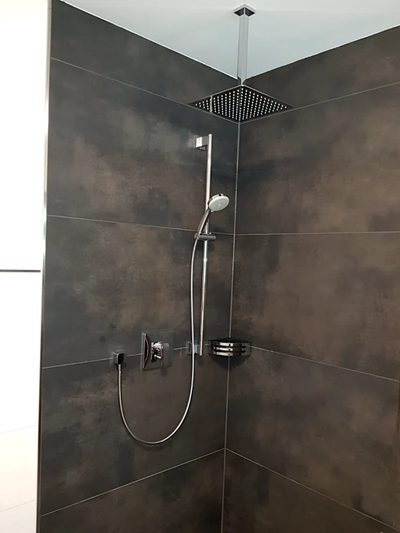 Dusche mit Regenduschkopf und Handbrause, dunkle Fliesen